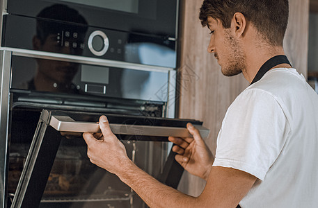 男人打开烤炉 在家庭厨房温度烧烤技术幸福活动男性烤箱玻璃检查美食图片