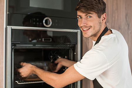 男人打开烤炉 在家庭厨房火炉快乐活动繁荣幸福温度烤箱技术男朋友房子图片