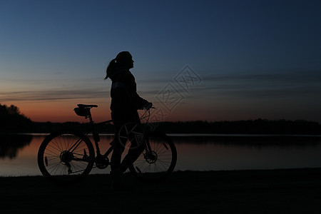 蓝色蓝天日落背景多彩的 骑着山上自行车的妇女的休眠轮运动假期墙纸女士海岸速度夕阳活力自由天空图片