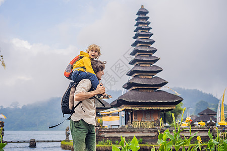 爸爸和儿子在巴厘岛的背景下 巴厘岛 Bratan 湖上被鲜花环绕的印度教寺庙 印度尼西亚巴厘岛的主要 Shivaite 水神庙 图片