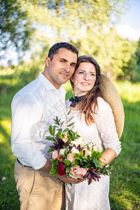 美丽的新婚夫妇站在绿色草地上 拥抱着彼此 生动的婚礼风格新娘花朵女士婚姻花束女性男人丈夫乡村庆典图片