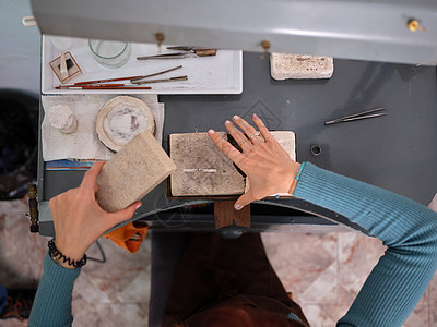 一位成年女性在她的工匠珠宝作坊工作 她坐在工作台前使用石块进行工作图片