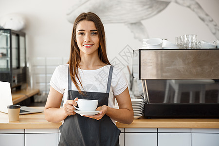 咖啡经营理念白人女性站在咖啡店里喝咖啡 专注于放置一杯咖啡的女性手咖啡师成人职员裁剪拿铁奉献柜台服务食物服务员图片