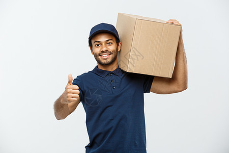 送货概念快乐的非洲裔美国人送货员拿着一个盒子包裹并出现重击的肖像 隔绝在灰色演播室背景 复制空间男生邮政运输纸板男性微笑团队工人图片