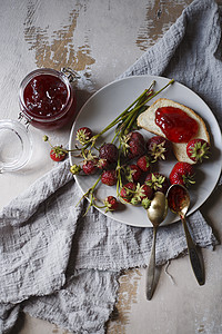 以草莓果酱 面包和灰色盘子上新鲜果浆的夏季早餐概念图片