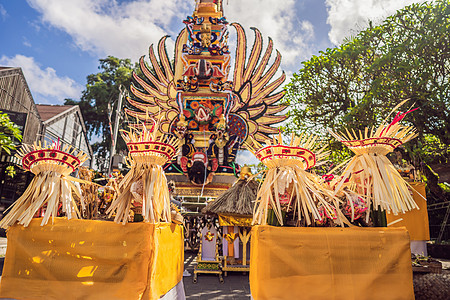 印度尼西亚巴厘岛乌布德市中央街道上 传统恶魔的拜林树雕塑和鲜花组成的巴德火化塔 为即将到来的火化仪式做准备面具上帝花环雕像旅行精图片