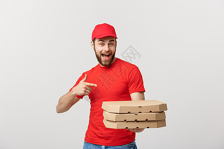 交付概念 英俊的caucasian披萨送货员用手指指着 在灰色背景上孤立无援眼睛职业工人幸福工作微笑成人服务盒子男人图片