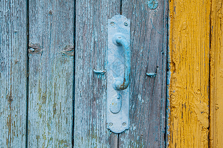 由木制门上的金属制成的旧蓝色门把手图片