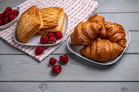 美味的新鲜糕点 木制桌子上的白盘子里有草莓美食早餐小吃饮料面包甜点杯子咖啡木板橙子图片