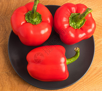 木板上黑色盘子里的三片甜辣椒作品营养白色小吃蔬菜团体食物美食绿色红色图片