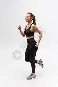 整个画面是一位运动女性 在工作室里跑过灰色背景运动装慢跑者活力健身房身体白色女士训练成人运动员图片