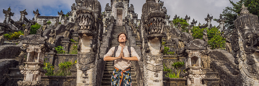 美丽的寺三座石梯背景下的年轻男子游客 与台阶的夏天风景到寺庙 Paduraksa 门户标志着的中间圣地的入口 巴厘岛横幅 长格式图片