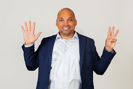成功的年轻非洲裔美国商务人士的画像 用手指向八号展示 微笑 自信和快乐 男人露出八根手指 8 号 站在灰色的背景上图片