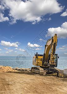 解构主义在海边建筑工地施工后在海上海滩的Crawler挖土机工程搬运工装载机拖拉机反铲机械车辆拆除推土机天空背景