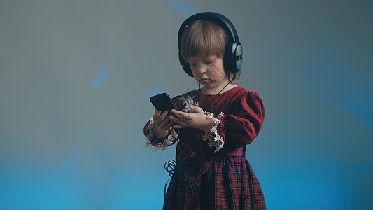 穿着大耳机和古代礼服的小女孩 在电话里听音乐宝宝乐器爱好裙子音乐复古玩家孩子衣服彩色图片