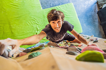 肌肉人练习在室内的岩石墙上攀岩安全闲暇登山绳索风险男性运动悬崖成人巨石图片