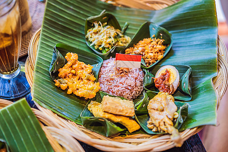 Nasi lemak Nasi campur 印度尼西亚巴厘岛米饭配土豆油条 沙爹百合 炸豆腐 辣煮鸡蛋和花生篮子香料传统竹子蔬图片