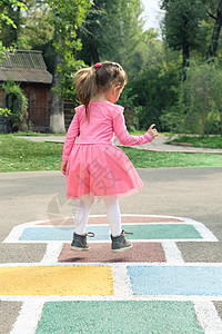 穿粉红色裙子的小女孩 在街上玩跳蚤舞数字黄色青菜蓝色青年沥青娱乐绘画游戏栅栏图片
