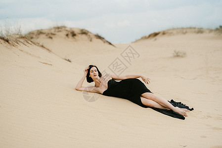 穿着黑色长裙的女孩 在沙沙沙漠裙子天空多样性头发沙漠背景化妆品跑步蓝色白色图片