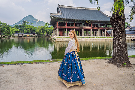 在韩国宫殿穿着韩服的年轻白人女游客 前往韩国的概念 韩国民族服装 游客娱乐试穿韩国民族服饰传统文化城市城堡国家历史性建筑学蓝色遗图片