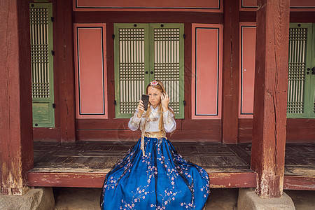 在韩国宫殿穿着韩服的年轻白人女游客 前往韩国的概念 韩国民族服装 游客娱乐试穿韩国民族服饰旅行微笑蓝色女孩文化城市女士地标裙子建图片