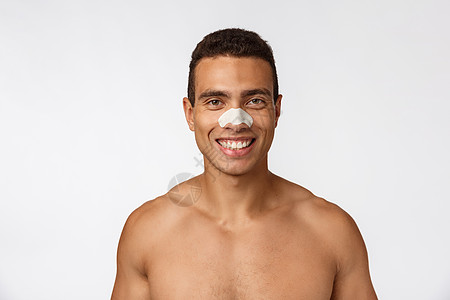 英俊的非洲人用鼻子补丁来减少黑点和皱纹 戴浴帽 笑容宽广爆炸工作室卫生奶油化妆品快乐男人外科皮肤微笑背景图片