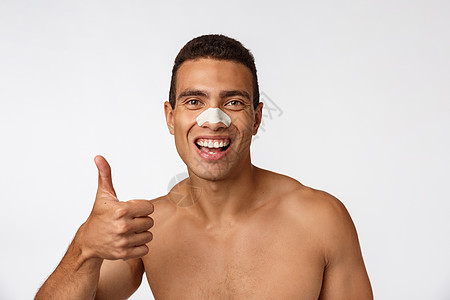 英俊的非洲人用鼻子补丁来减少黑点和皱纹 戴浴帽 笑容宽广手指成人男人清洁微笑外科工作室皮肤护理发型背景图片