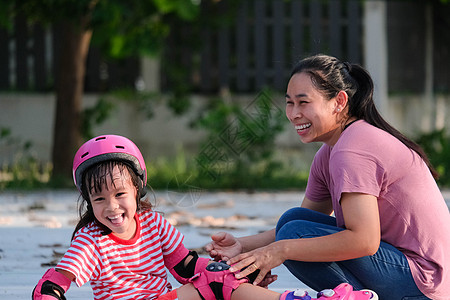 亚裔母亲帮助女儿在公园练习溜冰 为孩子们的户外活动提供启迪乐趣闲暇童年享受训练女孩平衡幼儿园运动装游戏图片
