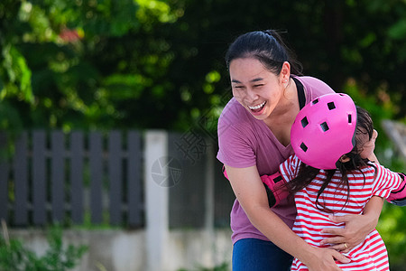 亚裔母亲帮助女儿在公园练习溜冰 为孩子们的户外活动提供启迪享受女性童年乐趣幸福训练安全爱好家庭溜冰鞋图片