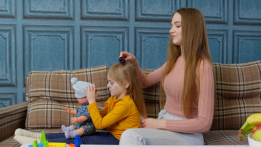 照顾母亲 在客厅为女儿女孩梳头发 玩玩具娃娃的小孩打孩子图片