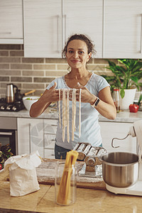 厨房里一个快乐的女人 展示了面条 由果汁搅拌机煮熟的面条图片