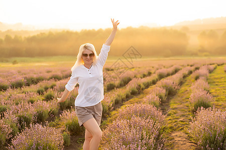 薰衣草纯露穿着草帽的金发年轻女旅行者 在熏衣草田里 围着紫色花朵露肩牛仔女性游客蓝色女孩短裤玫瑰天空薰衣草背景