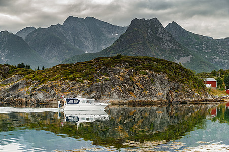 一艘白色的小渔船沿着岩石漂浮在水中 挪威海景 多岩石的海岸和戏剧性的天空 阳光穿过云层 陡峭的悬崖蓝色旅行假期旅游海岸线海洋支撑图片