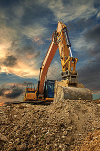解构主义日落时在建筑工地进行挖土施工期间的Crawler挖土机岩石拆除车辆搬运工工程机械土壤推土机天空力量背景