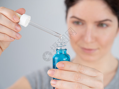 白种女人使用蓝色抗皱脸血清卫生吸管清洁女性皱纹软膏女孩化妆品护理治疗背景图片
