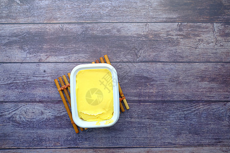 木制表格顶视图的容器中的新鲜黄油图片