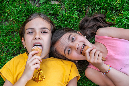 女孩吃冰淇淋孩子们在公园里吃冰淇淋乐趣孩子女孩微笑巧克力海滩女士太阳幸福喜悦背景