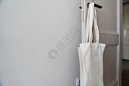 白色生态友好袋挂在门把手上 罐装袋嘲笑手提包设计顾客小样亚麻背景纺织品模板样机图片