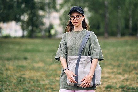 戴眼镜的年轻女子 拿着空棉花生态袋 模型设计木材回收材料帆布包样机纹理手提袋手提包女孩亚麻图片