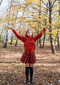 年轻快乐的女子扔树叶 在秋林乐趣橙子微笑公园森林闲暇季节幸福女士成人图片