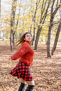 年轻快乐的少女在秋林中行走女士叶子幸福微笑树木森林女性乐趣喜悦公园图片