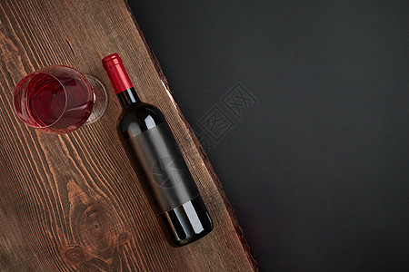 黑色背景的木板上装满一瓶酒和一杯玻璃 带有复制空间的顶端视图图片