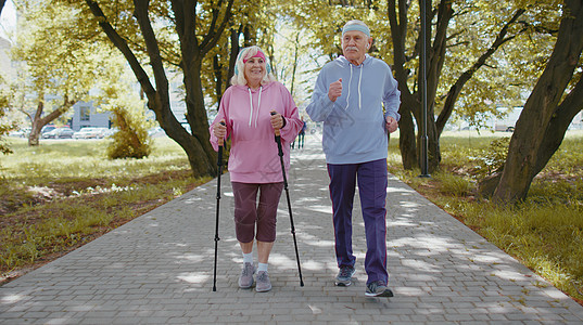 活跃的高级祖父母培训北欧人步行滑雪 在夏季公园跑动 在冬季公园运行奶奶慢跑者娱乐退休有氧运动女士远足活动活力老年背景图片
