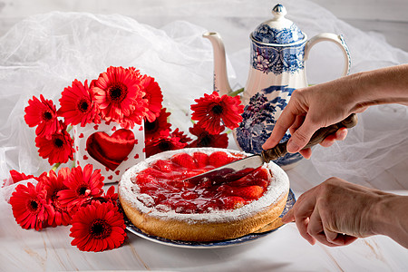 女人把草莓馅饼切在桌子上 上面装饰着红斑马图片