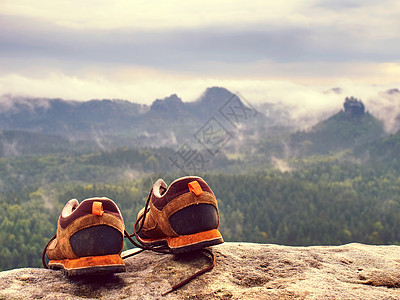 山前岩石上的棕色远足靴子图片
