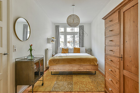 宽敞明亮的卧室 有古老的床边桌子和衣橱图片