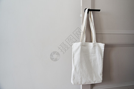 白色生态友好袋挂在门把手上 罐装袋亚麻背景木材纹理纺织品样机棉布手提袋帆布象牙图片