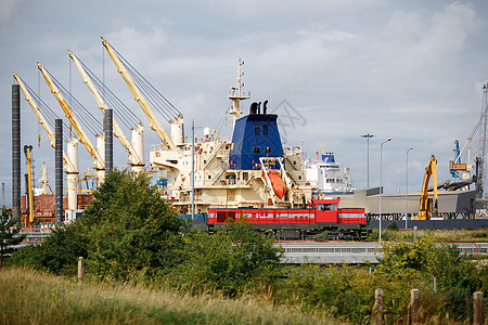 港口起重机和海运集装箱在货物海港卸载 前方是一辆红色蒸汽机车 在铁路上运行码头贸易蓝色海洋船运货船加载物流卡车送货图片