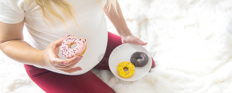 孕妇吃甜甜甜圈 有选择性的焦点饮食女士怀孕横幅肚子垃圾成人甜甜圈营养早餐图片