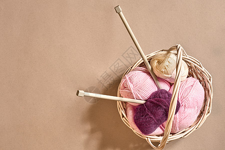 毛线球 柳条盘中的彩色纱线球 用于在米色背景上编织的纱线 针织作为一种针线活 织针和多色纱线看起来很明亮衣服艺术紫色作品褐线彩线图片